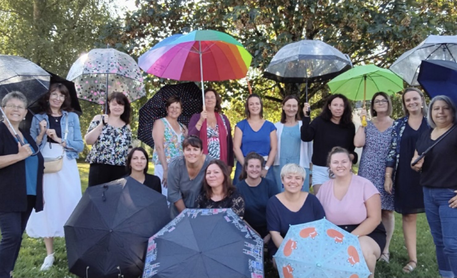 L’équipe de l’école réunie dans le parc, chacune tenant un parapluie coloré