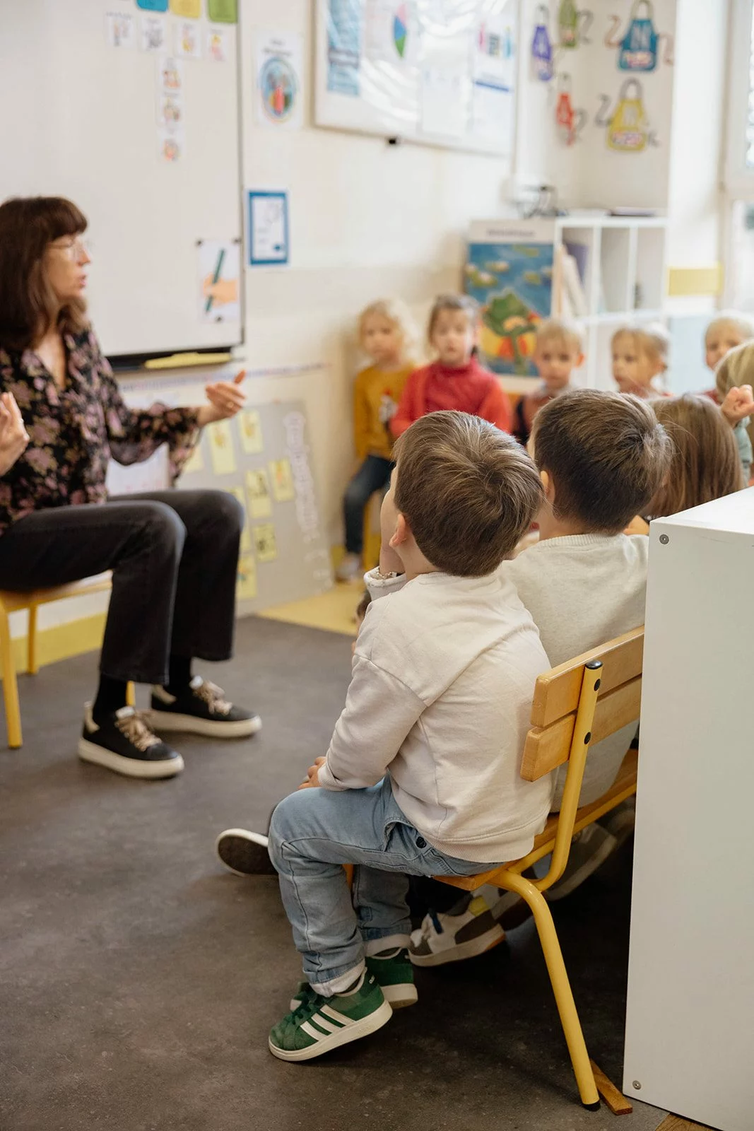 Une enseignante de maternelle mene un temps de chant, sa classe assise face a elle