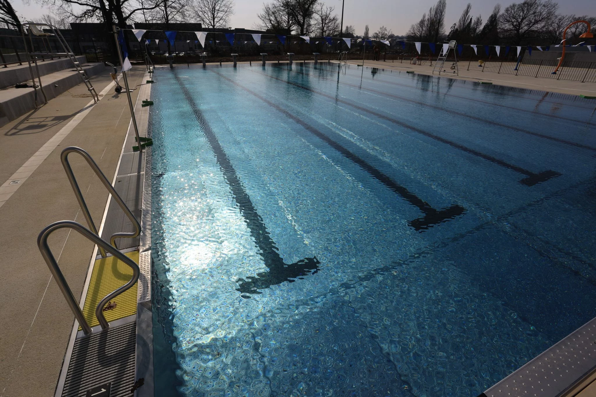 Le bassin exterieur de la piscine, vide, avec ses lignes d'eau et ses fanions bleus et blancs