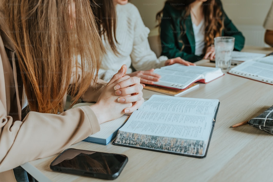 Des mains posees de part et d autre d un livre ouvert, autour d une table de travail
