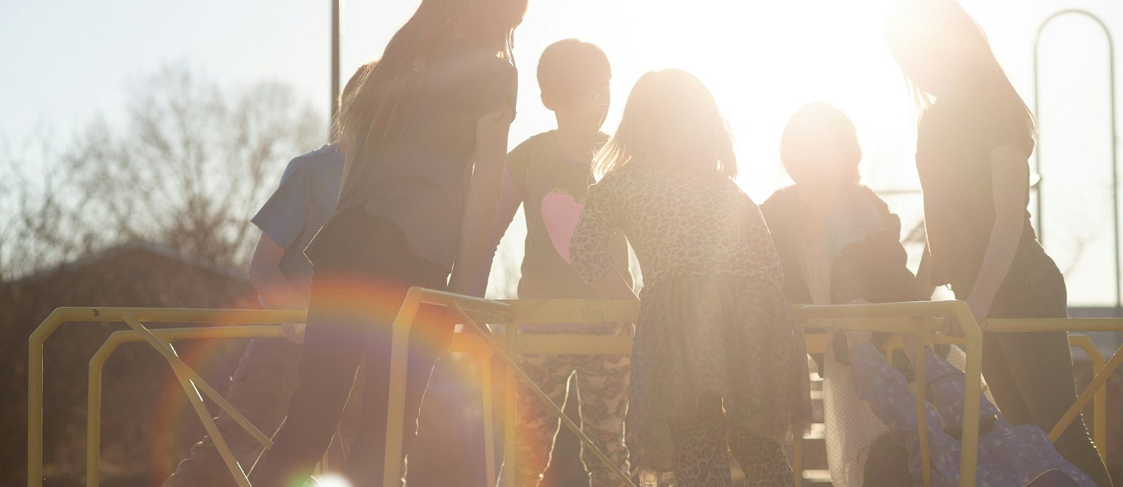 Un groupe d enfants reunis autour d une table de jeu en exterieur, a contre-jour dans le soleil